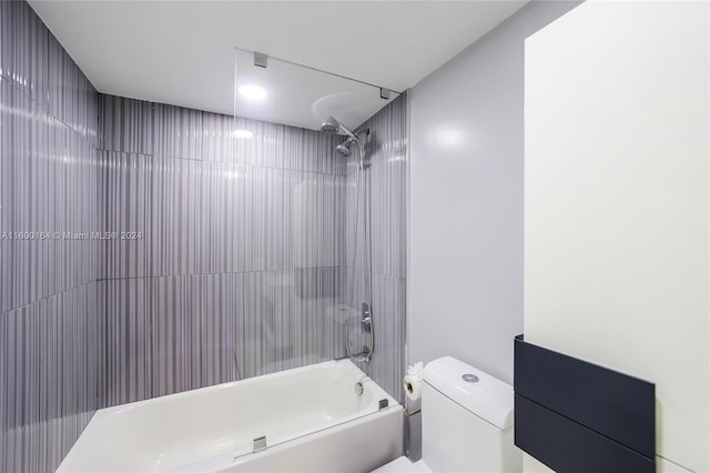 bathroom featuring toilet and tiled shower / bath