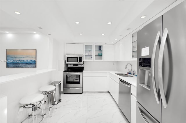 kitchen with appliances with stainless steel finishes, white cabinetry, light tile patterned floors, and sink