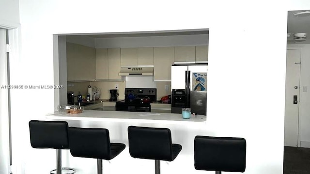 kitchen featuring black electric range oven, kitchen peninsula, a kitchen bar, and stainless steel fridge with ice dispenser