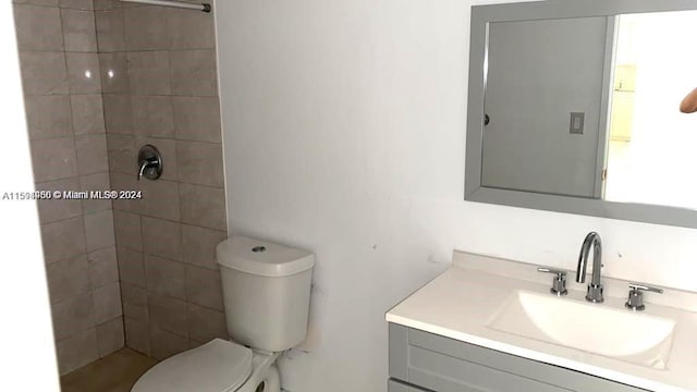 bathroom featuring a tile shower, vanity, and toilet