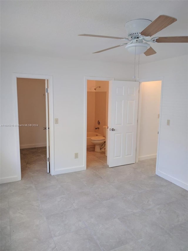 unfurnished bedroom featuring a spacious closet, ensuite bathroom, ceiling fan, and light tile patterned floors