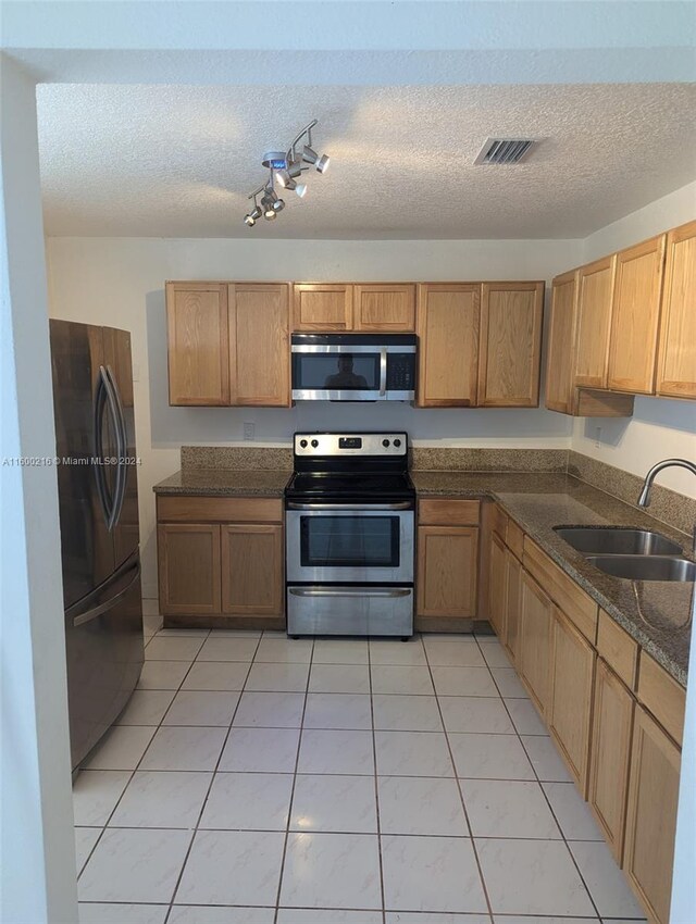 kitchen with sink, appliances with stainless steel finishes, a textured ceiling, and light tile patterned floors