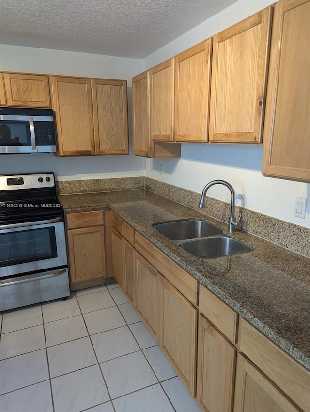 kitchen with light tile patterned flooring, appliances with stainless steel finishes, sink, and a textured ceiling