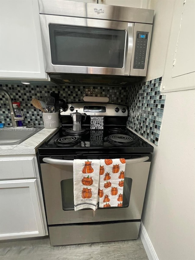 kitchen featuring sink, white cabinets, decorative backsplash, and stainless steel appliances