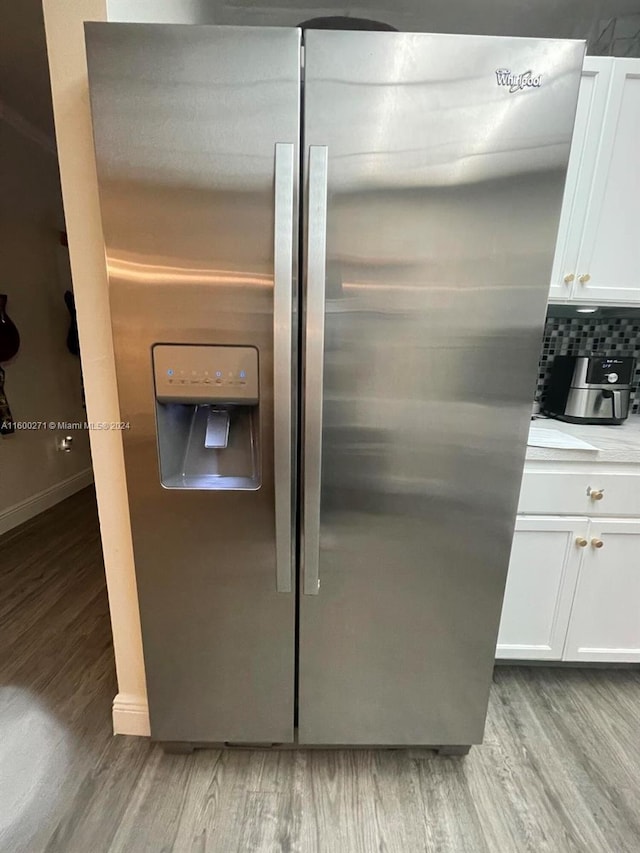 details featuring white cabinetry, backsplash, hardwood / wood-style floors, and stainless steel refrigerator with ice dispenser