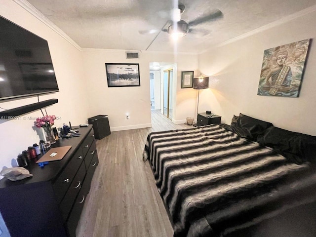 bedroom featuring ceiling fan, crown molding, a textured ceiling, and hardwood / wood-style flooring