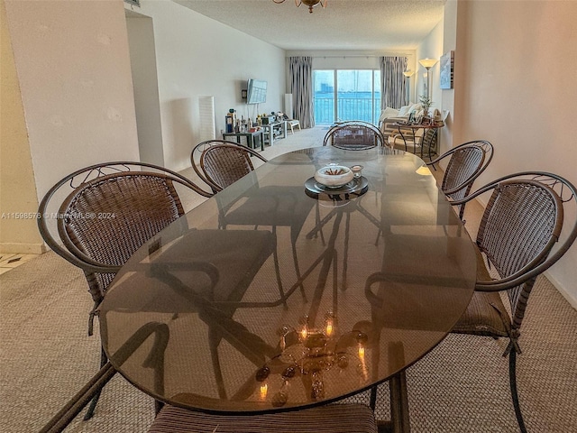 carpeted dining space with a textured ceiling