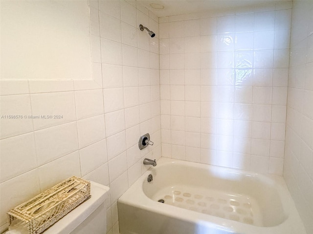 bathroom with tiled shower / bath combo and tile walls