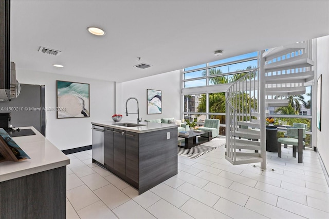 kitchen featuring dark brown cabinetry, a center island with sink, stainless steel appliances, and sink