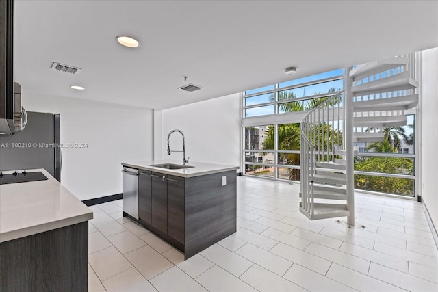 kitchen with dark brown cabinets, floor to ceiling windows, sink, and an island with sink