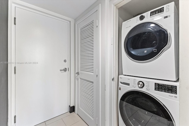 laundry room featuring stacked washing maching and dryer and light tile patterned flooring