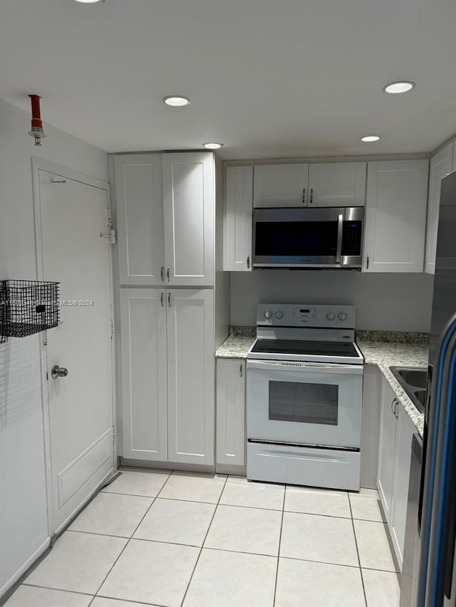 kitchen with light tile patterned flooring, light stone countertops, and appliances with stainless steel finishes