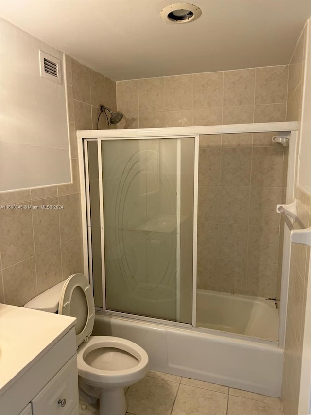 full bathroom with toilet, tile walls, tile patterned flooring, shower / bath combination with glass door, and vanity