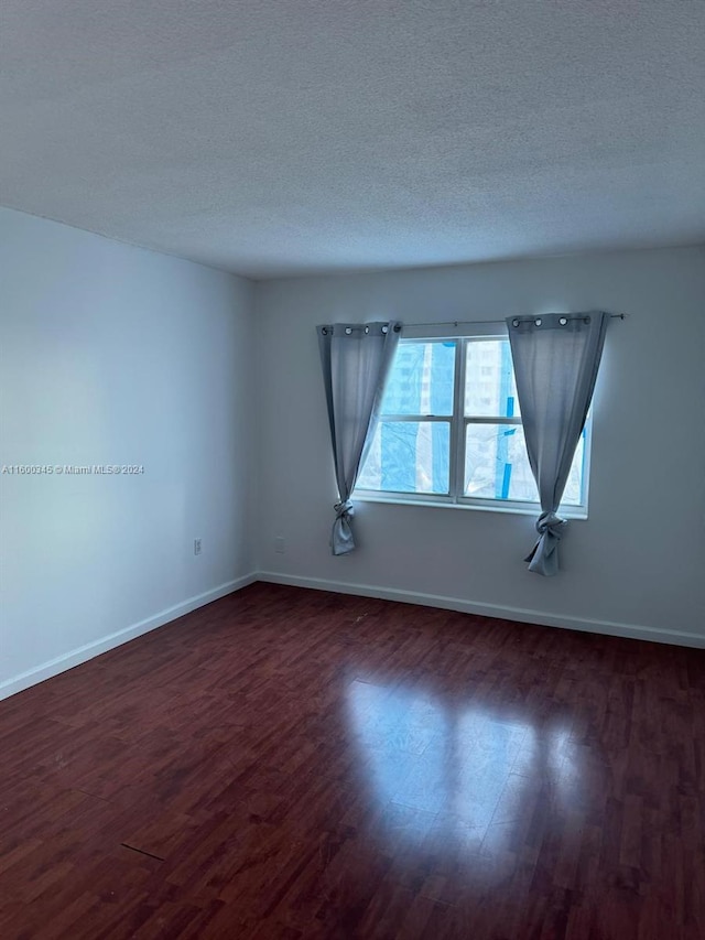 empty room featuring dark hardwood / wood-style flooring and a textured ceiling