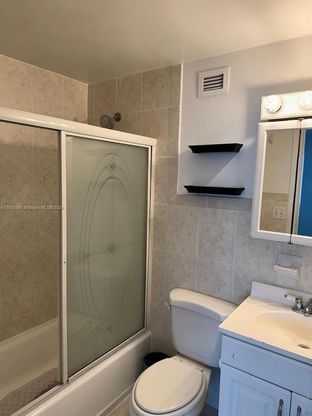 full bathroom with tile walls, shower / bath combination with glass door, and vanity