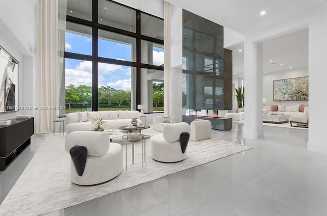 tiled living room featuring a towering ceiling and expansive windows