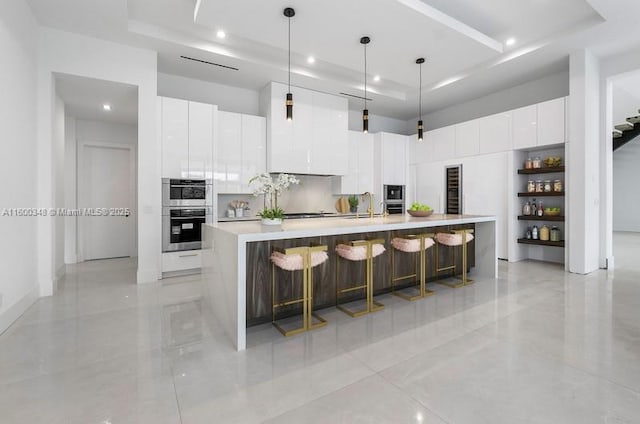 kitchen featuring a tray ceiling, modern cabinets, and stainless steel double oven