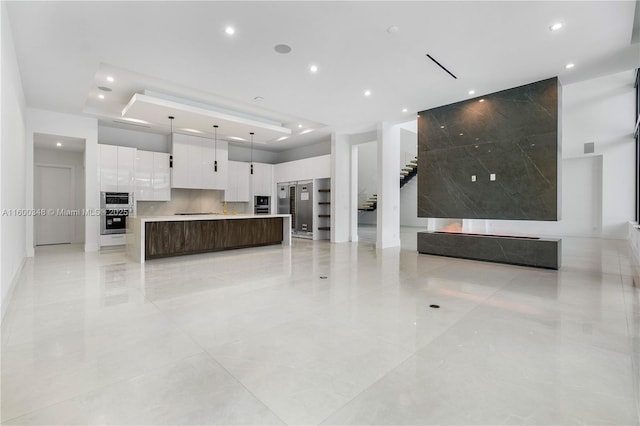 kitchen with a spacious island, open floor plan, light countertops, white cabinets, and modern cabinets