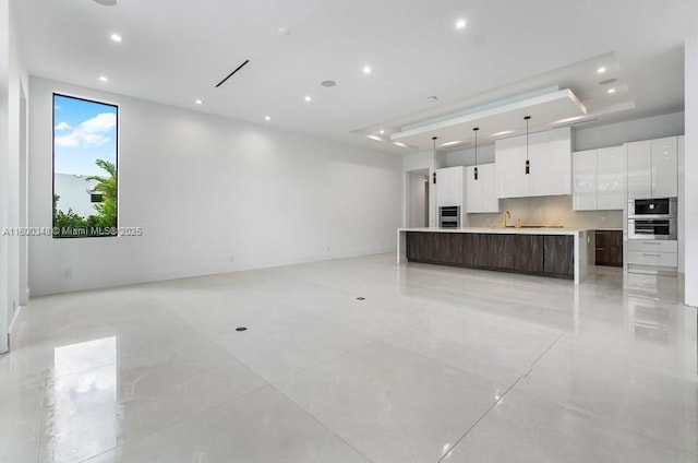 kitchen with a spacious island, dark brown cabinets, open floor plan, white cabinets, and modern cabinets