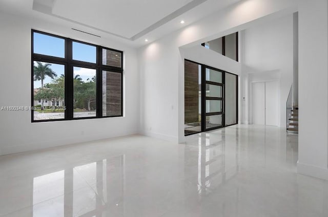 unfurnished room with stairway, baseboards, a high ceiling, and marble finish floor