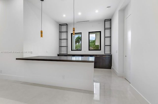 interior space featuring baseboards, a peninsula, recessed lighting, hanging light fixtures, and dark countertops