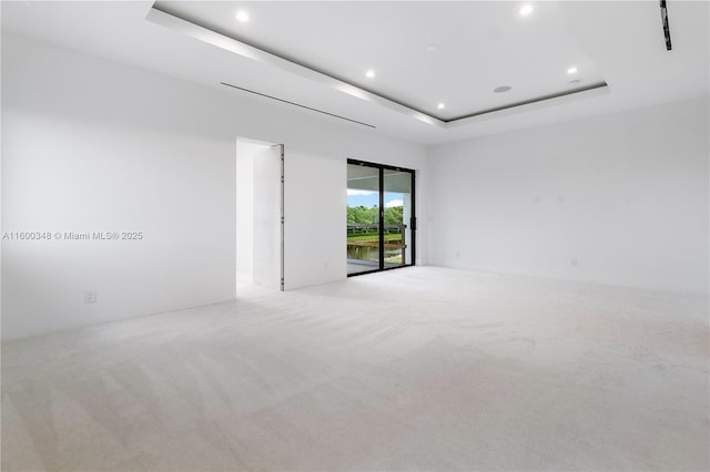 carpeted empty room featuring recessed lighting and a raised ceiling