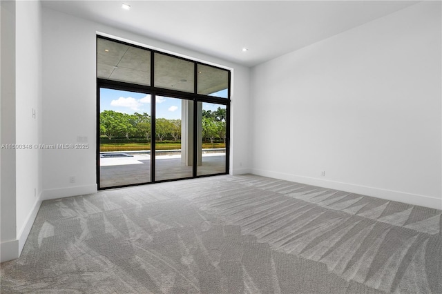 spare room featuring a wall of windows, carpet flooring, recessed lighting, and baseboards