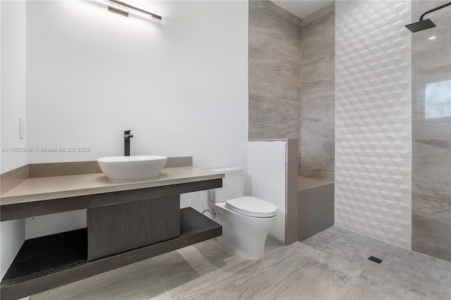 bathroom with toilet, vanity, and a tile shower