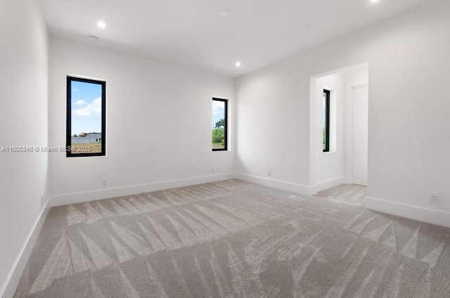 unfurnished room with light carpet, recessed lighting, and baseboards