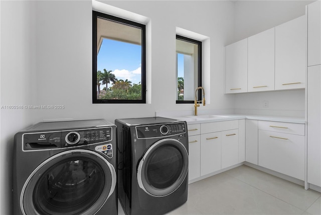 laundry room featuring cabinet space, washing machine and dryer, and a sink