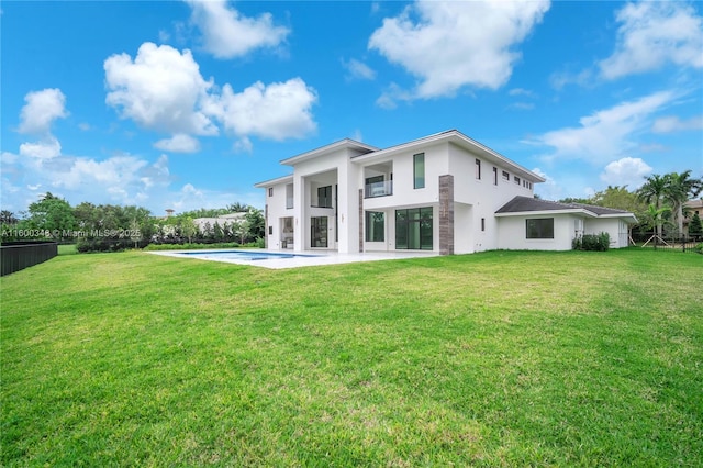 back of property with a patio, fence, an outdoor pool, stucco siding, and a lawn