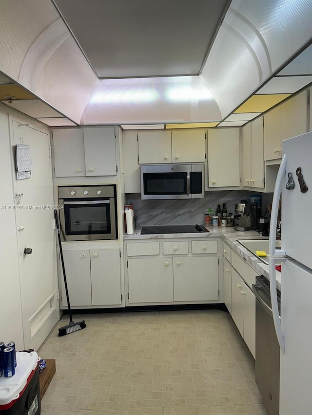 kitchen featuring backsplash, appliances with stainless steel finishes, and light tile flooring