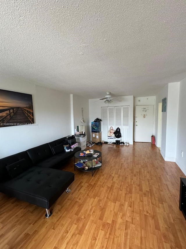 living room featuring light hardwood / wood-style floors, a textured ceiling, and ceiling fan