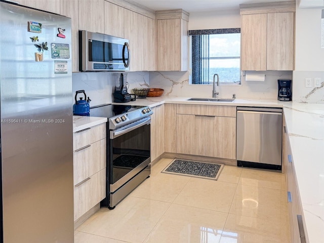 kitchen featuring light tile patterned flooring, sink, decorative backsplash, stainless steel appliances, and light brown cabinets