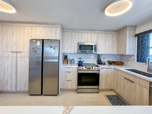 kitchen with appliances with stainless steel finishes, sink, and light brown cabinets