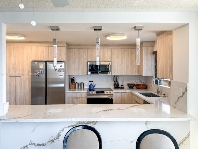 kitchen featuring light brown cabinetry, sink, pendant lighting, stainless steel appliances, and light stone countertops