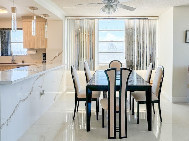 tiled dining area featuring sink, a textured ceiling, and ceiling fan