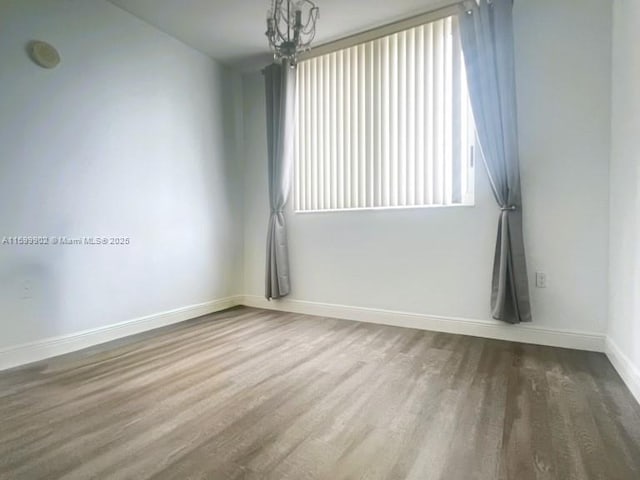 unfurnished room with hardwood / wood-style flooring and a chandelier