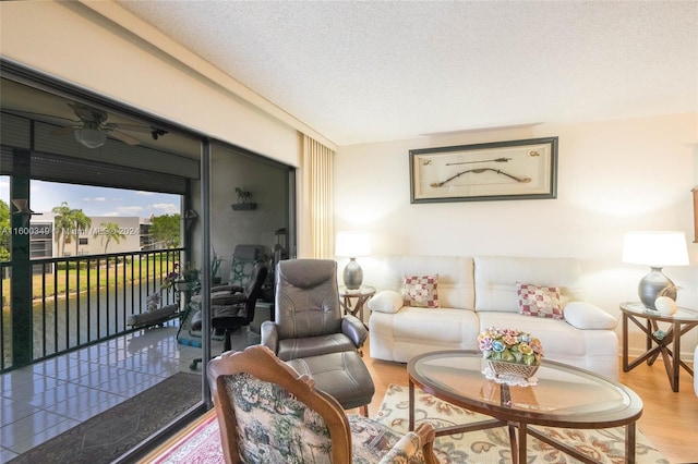 living room featuring ceiling fan, hardwood / wood-style flooring, and a textured ceiling