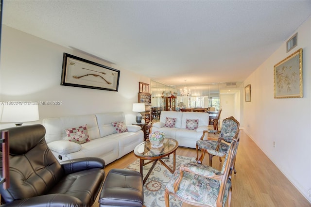 living room featuring a notable chandelier, a textured ceiling, and hardwood / wood-style floors