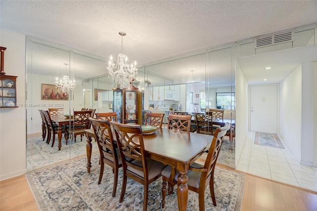 dining space with a textured ceiling, light tile floors, and a chandelier