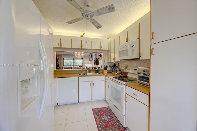 kitchen with a textured ceiling, white appliances, light tile flooring, and ceiling fan with notable chandelier