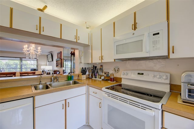 kitchen with a textured ceiling, sink, white cabinets, and white appliances