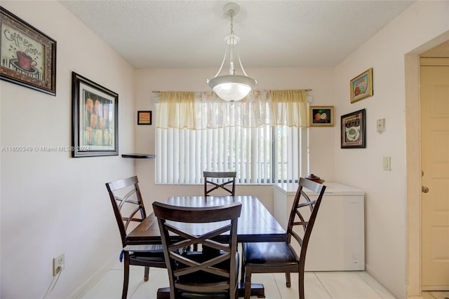 dining area with a textured ceiling and light tile flooring