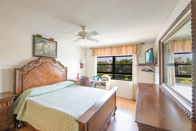 bedroom with hardwood / wood-style floors, ceiling fan, and a textured ceiling