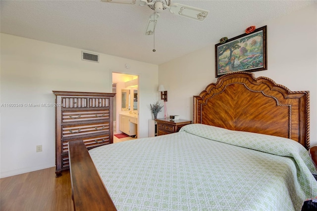 bedroom with hardwood / wood-style flooring, ensuite bathroom, ceiling fan, and a textured ceiling