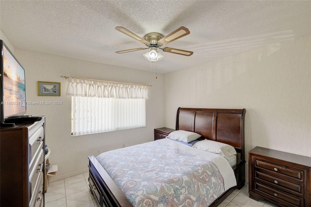 tiled bedroom with ceiling fan and a textured ceiling