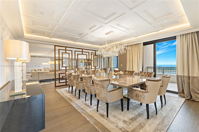 dining room with coffered ceiling, a chandelier, hardwood / wood-style flooring, a water view, and ornamental molding