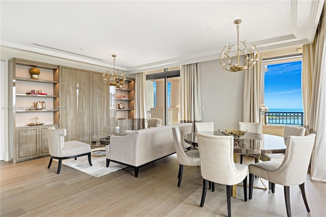 dining room with a chandelier, crown molding, light wood-style flooring, and built in shelves