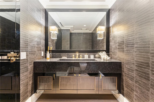 bathroom featuring vanity, crown molding, and tile walls